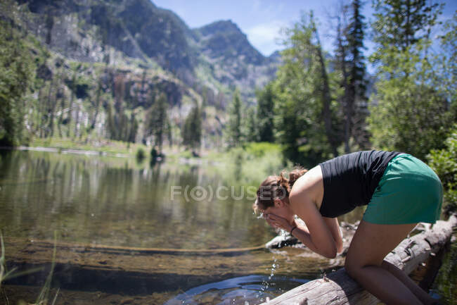 Hiker lavado de la cara en el arroyo, Encantamientos, Alpine Lakes Wilderness, Washington, EE.UU. - foto de stock