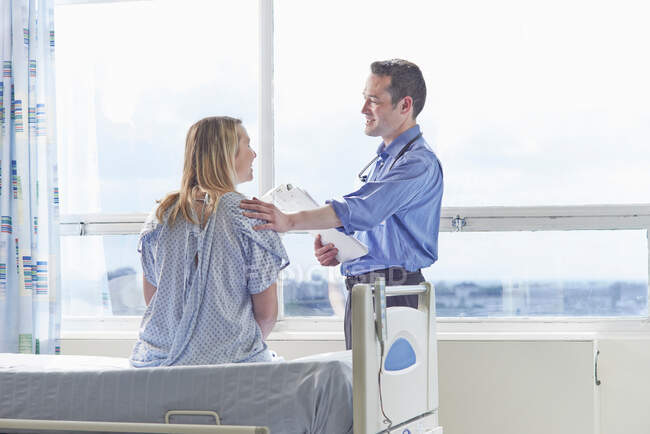 Médecin parlant à un patient assis sur un lit d'hôpital — Photo de stock
