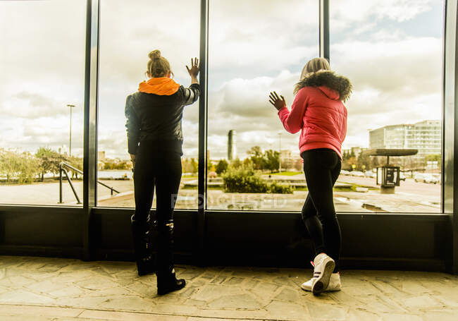 Two female friends looking out of window — Stock Photo