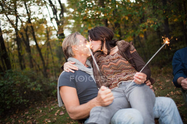 Mature couple kissing with sparklers — Stock Photo