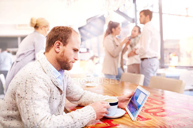 Junger Mann allein im Café und schaut auf digitales Tablet — Stockfoto