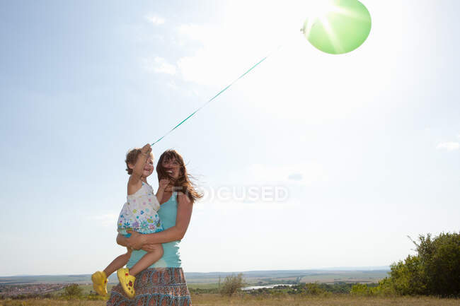 Madre e figlia che trasportano palloncino — Foto stock