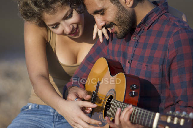Jeune couple, homme jouant de la guitare — Photo de stock