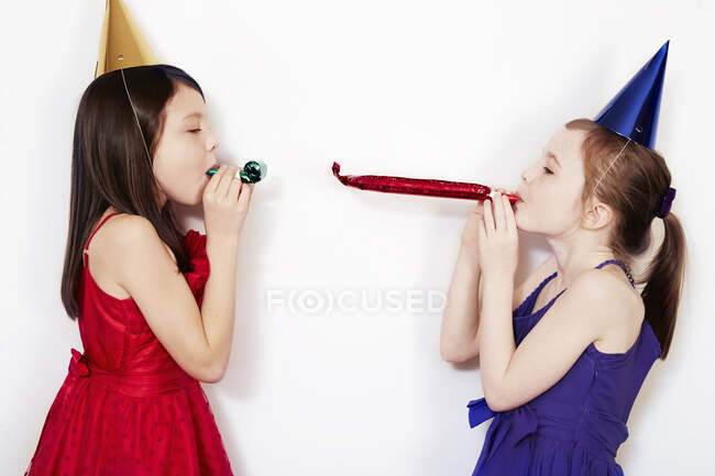 Retrato de dos chicas soplando sopladores de fiesta - foto de stock