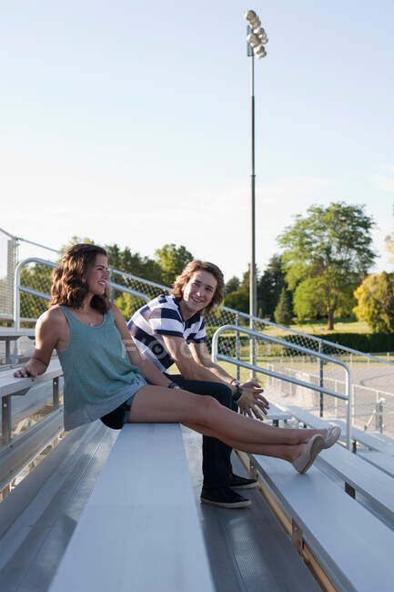 Adolescente casal sentado em bancadas — Fotografia de Stock