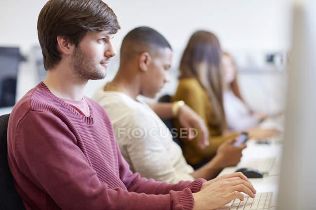 Estudiantes escribiendo en computadoras en la sala de computadoras de la universidad de educación superior - foto de stock