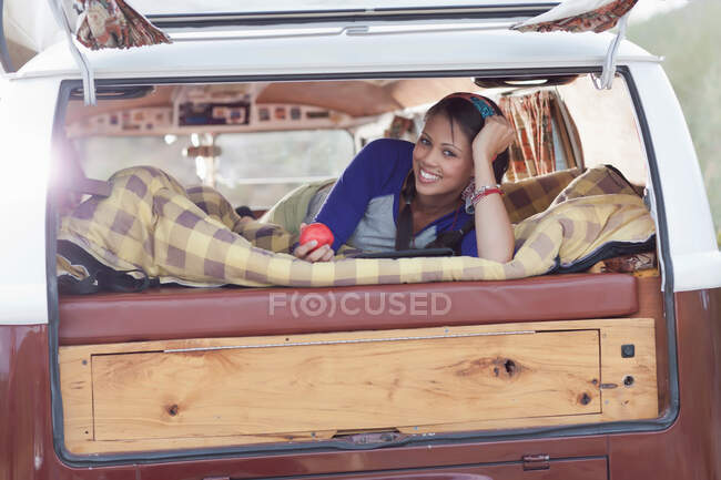 Молода жінка лежить у фургоні, посміхаючись — стокове фото