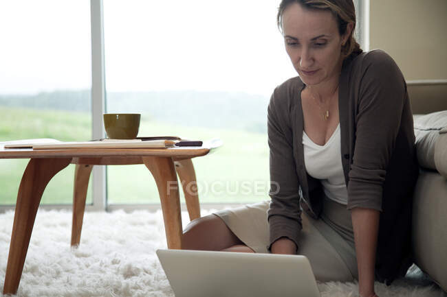 Жінка сидить на підлозі за допомогою ноутбука — стокове фото