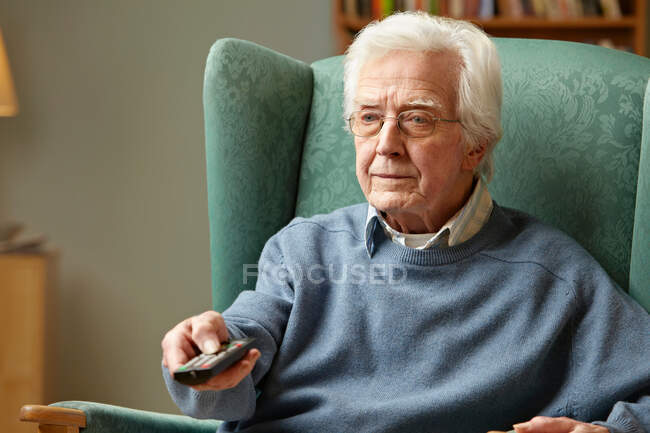 Senior man using remote control — Stock Photo