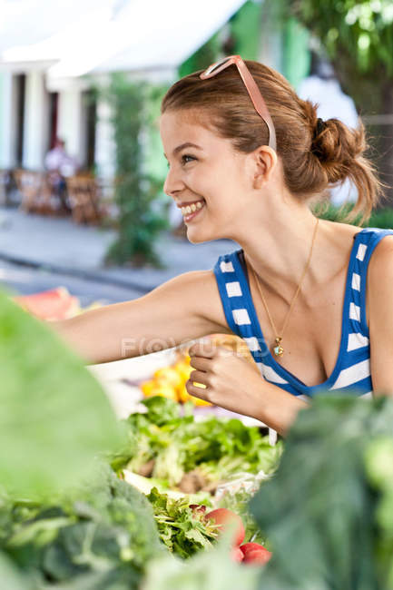 Young woman buying vegetables in market — Stock Photo
