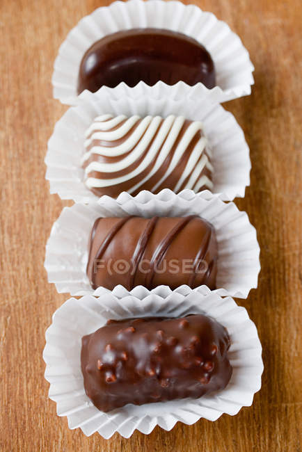 Wrapped chocolate candies in a row on table — Stock Photo