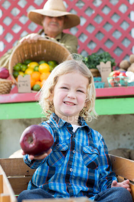 Boy holding apple at farmer's market — Stock Photo