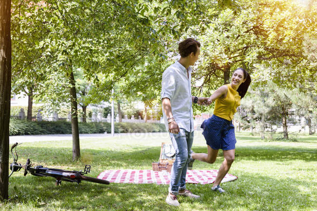Young couple on picnic frolicking in park — Stock Photo