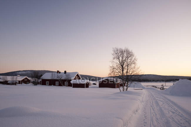 Belo pôr do sol no telhado da aldeia na neve — Fotografia de Stock