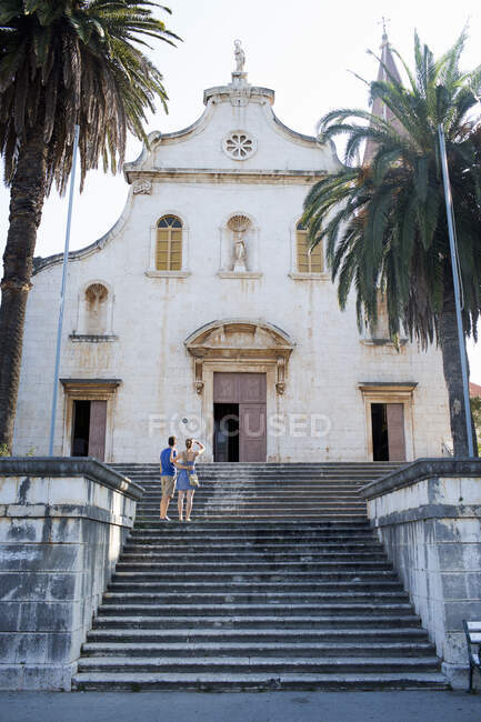 Rear view of young couple looking up at church, Milna, Brac, Croatia — Stock Photo