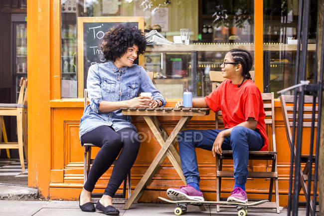 Мальчик и мать сидят в кафе на тротуаре — стоковое фото