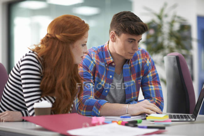 Молодые девушки и студенты колледжа смотрят на ноутбук на столе — стоковое фото
