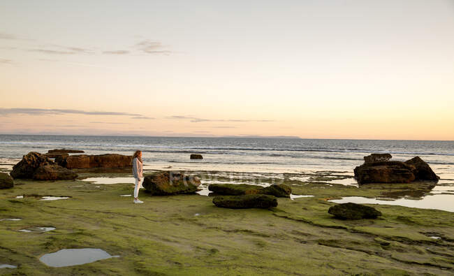 Donna che guarda il tramonto dalla spiaggia rocciosa, Capo di Trafalgar, Spagna — Foto stock