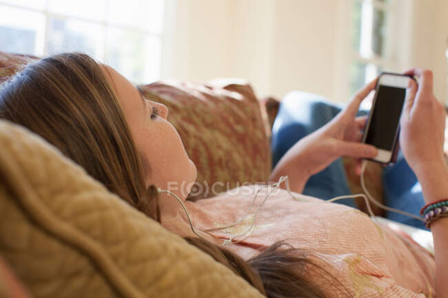 Adolescente deitada no sofá com fones de ouvido — Fotografia de Stock