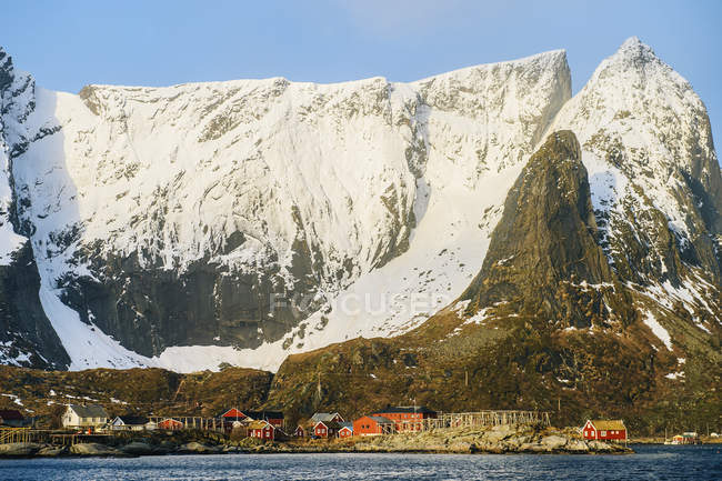Edificios bajo montañas nevadas a la luz del sol - foto de stock