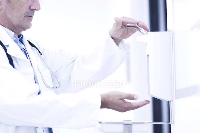 Médico masculino usando desinfectante de manos - foto de stock