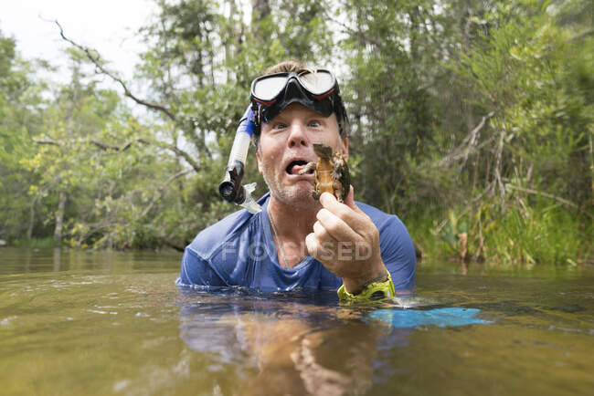 Man in water holding mud turtle, pulling face, Turkey Creek, Niceville, Florida, USA — Stock Photo