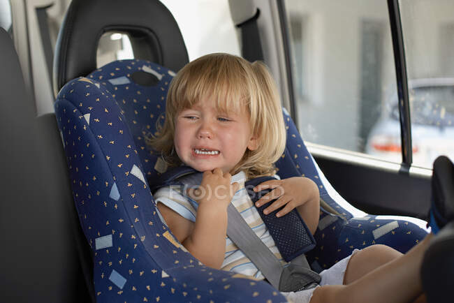 Young girl crying in her car seat — Stock Photo