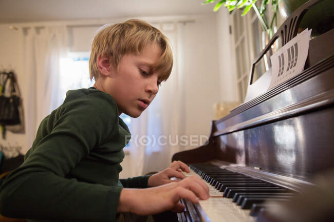 Boy playing piano in living room — Stock Photo