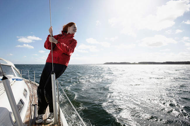 Giovane donna aggrappata alla corda sullo yacht — Foto stock