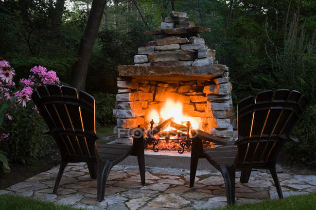 Two chairs in front of outdoor fireplace — Stock Photo
