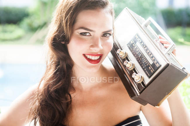 Молода жінка тримає старовинне радіо і посміхається на камеру — стокове фото