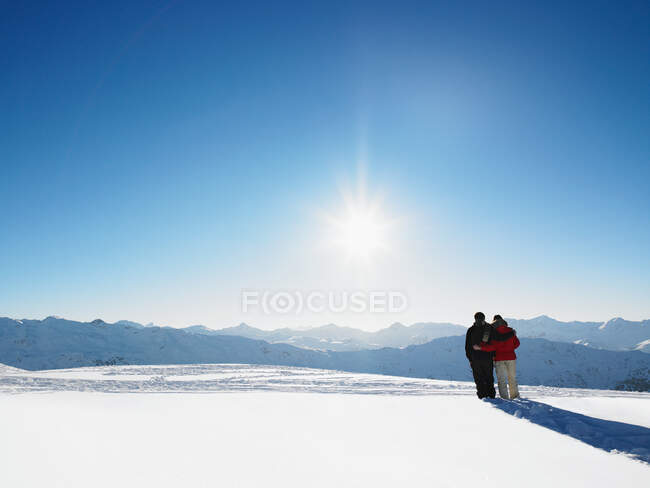 Pareja caminando en la nieve en la cima de la montaña - foto de stock