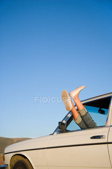 Pieds féminins sortant de la fenêtre de la voiture — Photo de stock