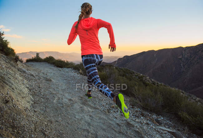 Vista posteriore del sentiero di giovane donna che corre su pista sterrata al crepuscolo sul Pacific Crest Trail, Pine Valley, California, USA — Foto stock