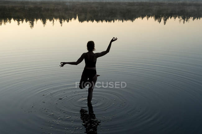 Mulher em ioga posar no lago — Fotografia de Stock