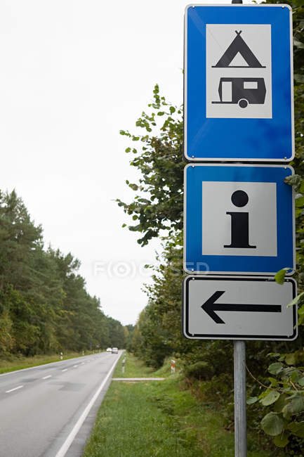 Vista de três sinais no fundo da estrada e árvores — Fotografia de Stock