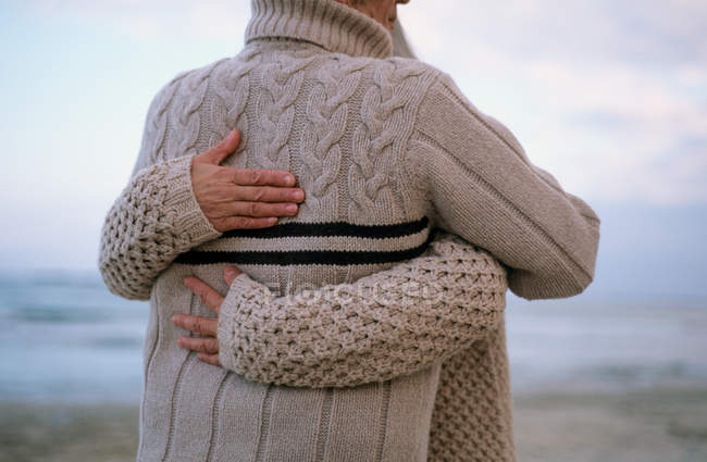 Visão traseira do casal abraçando na praia — Fotografia de Stock