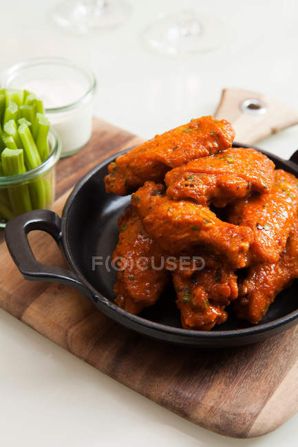 Dish of roasted chicken wings on wooden board — Stock Photo