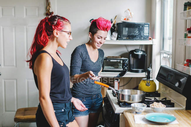 Дві молоді жінки готують їжу на кухонній плиті — стокове фото