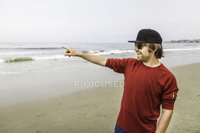 Junger Mann zeigt aufs Meer, Laguna Beach, Kalifornien, USA — Stockfoto