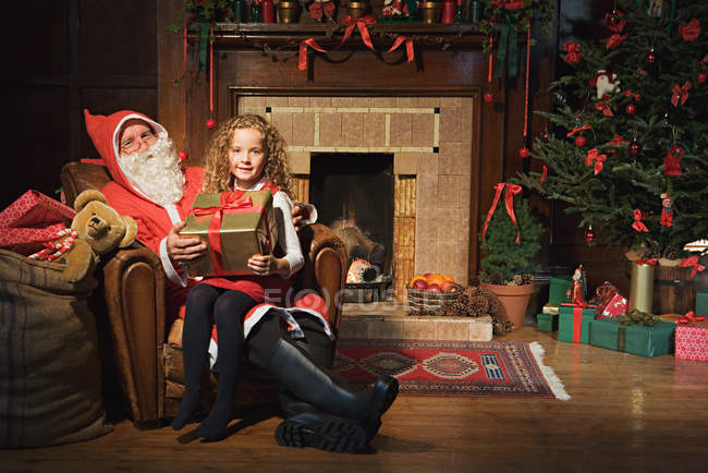 Papai Noel dando a menina um presente — Fotografia de Stock