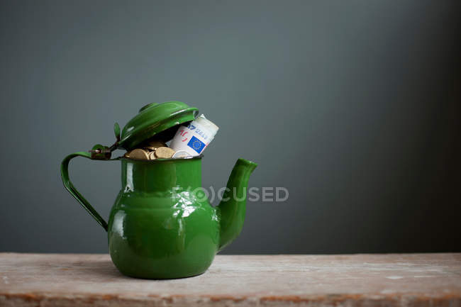 Teapot with euros banknotes and coins — Stock Photo