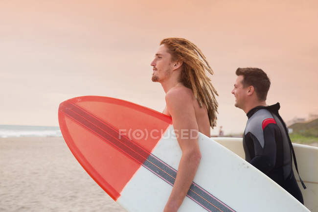 Guarda-vidas masculina e surfista olhando para o mar a partir da praia — Fotografia de Stock
