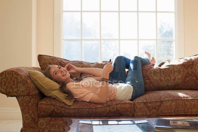Teenager-Mädchen liegt mit Kopfhörern auf Sofa — Stockfoto