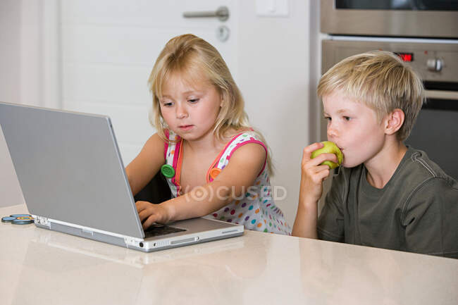 A brother and sister using a laptop — Stock Photo
