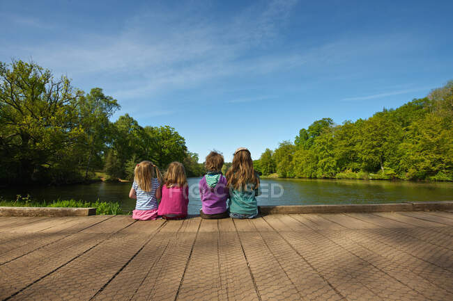 Дети сидят на деревянном причале в озере — стоковое фото