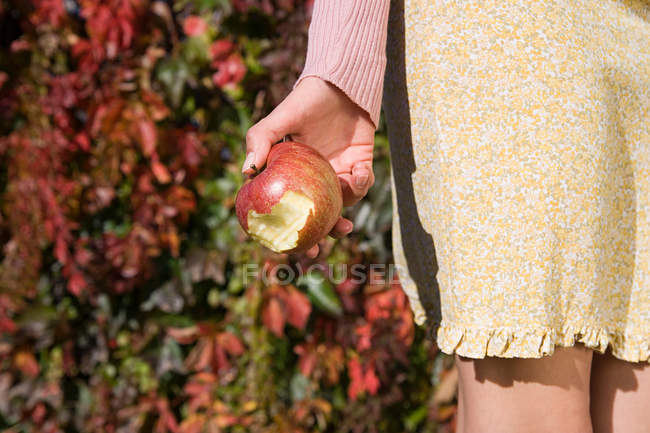 Imagen recortada de Mujer sosteniendo manzana mordida - foto de stock