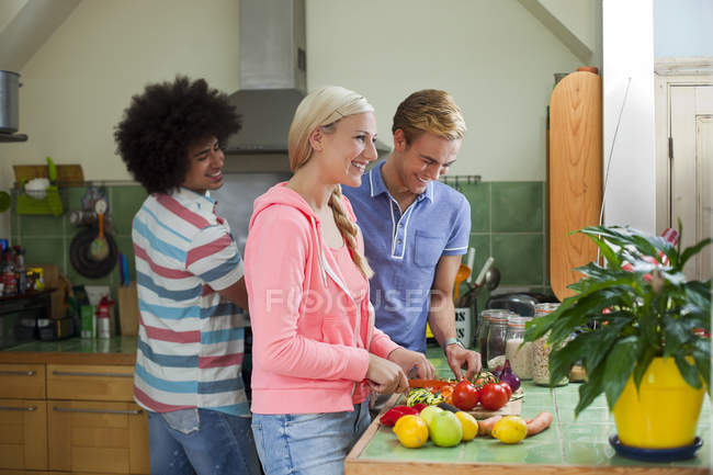 Group of friends preparing vegetables in kitchen — Stock Photo