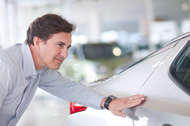 Retrato del hombre examinando el coche en la sala de exposición - foto de stock