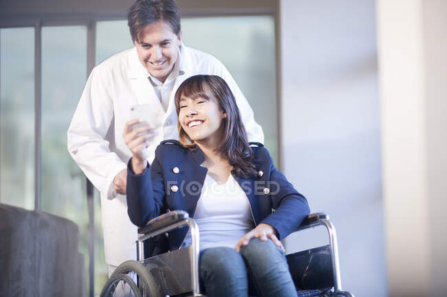Mulher em cadeira de rodas assistida por enfermeiro — Fotografia de Stock